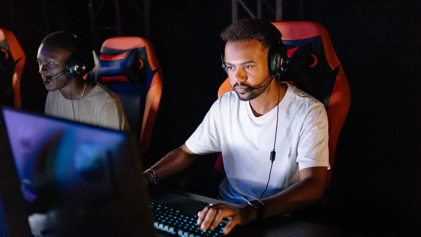 Två spelare med headset mitt i en e-sportmatch i ett mörkt rum