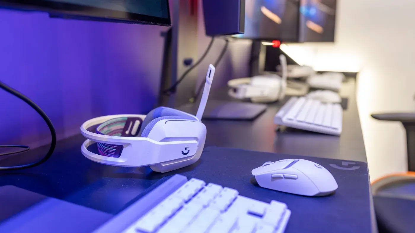Vitt headset, mus och tangentbord på ett skrivbord i färgstark belysning