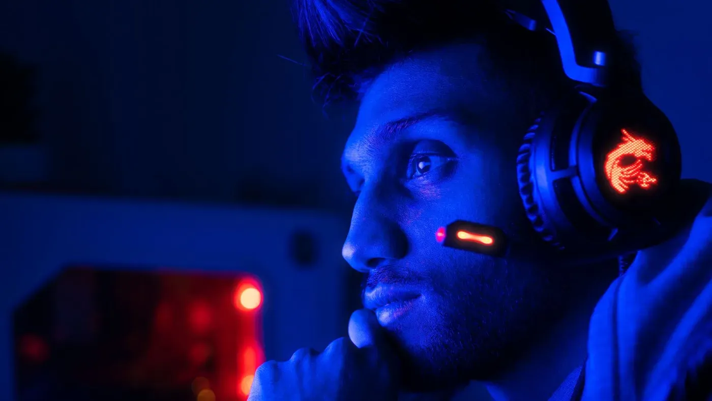 Fokuserad spelare med headset i blått ljus.