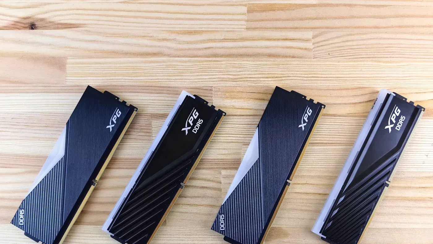 Fyra XPG DDR5-minnesmoduler i rad på en träyta.