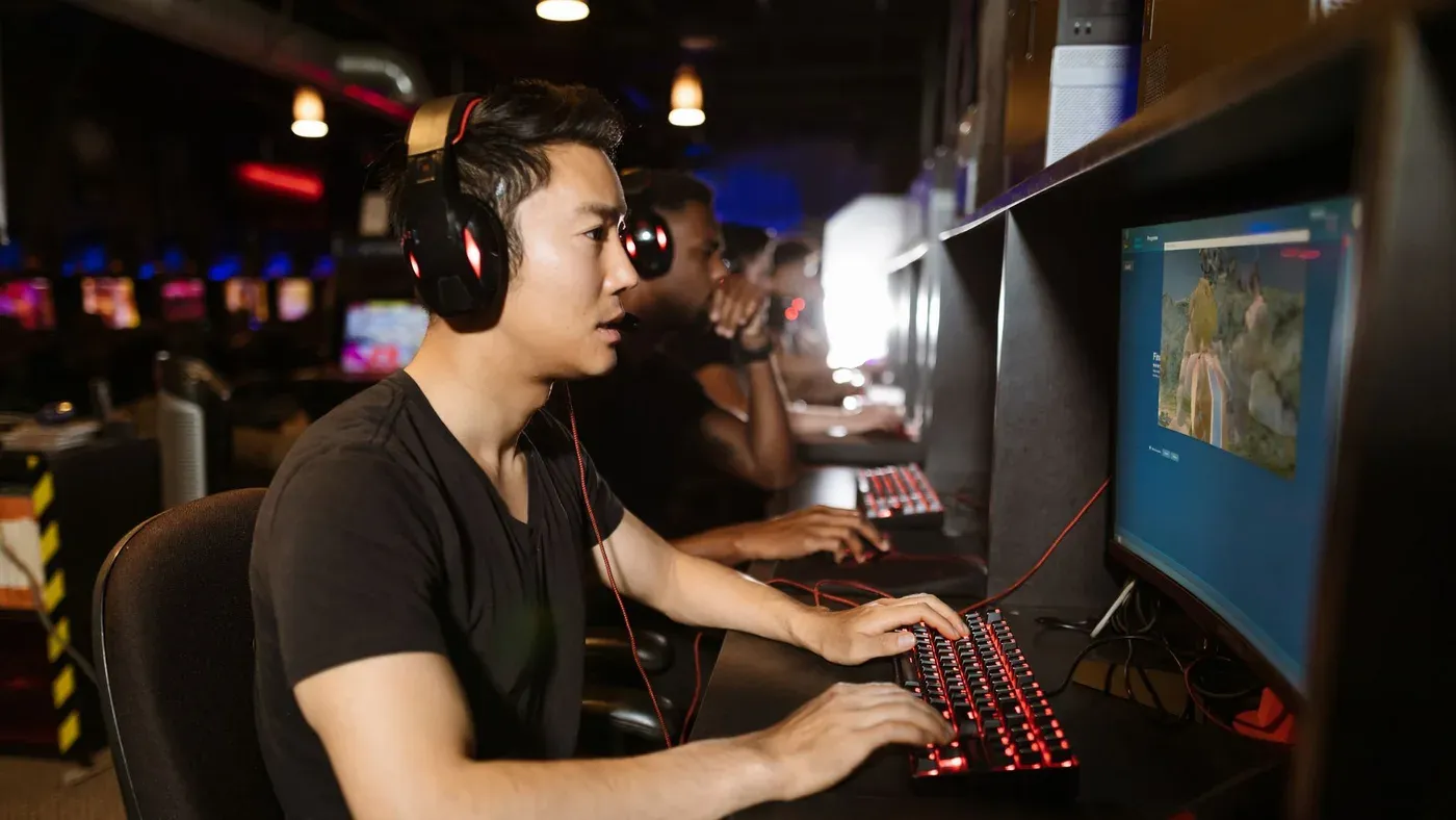 Grupp män spelar dator på ett internetcafé.