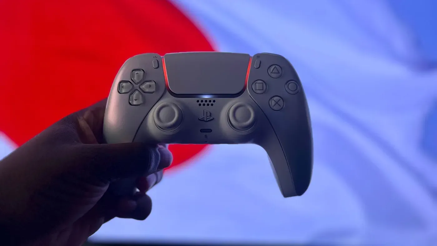 En Playstation 5 DualSense-handkontroll hålls upp framför en flagga.
