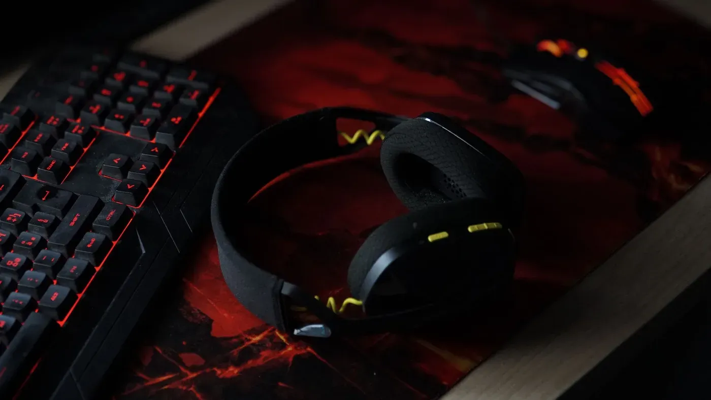 Gamingplats med belyst tangentbord, trådlöst headset och mus på en färgstark musmatta.