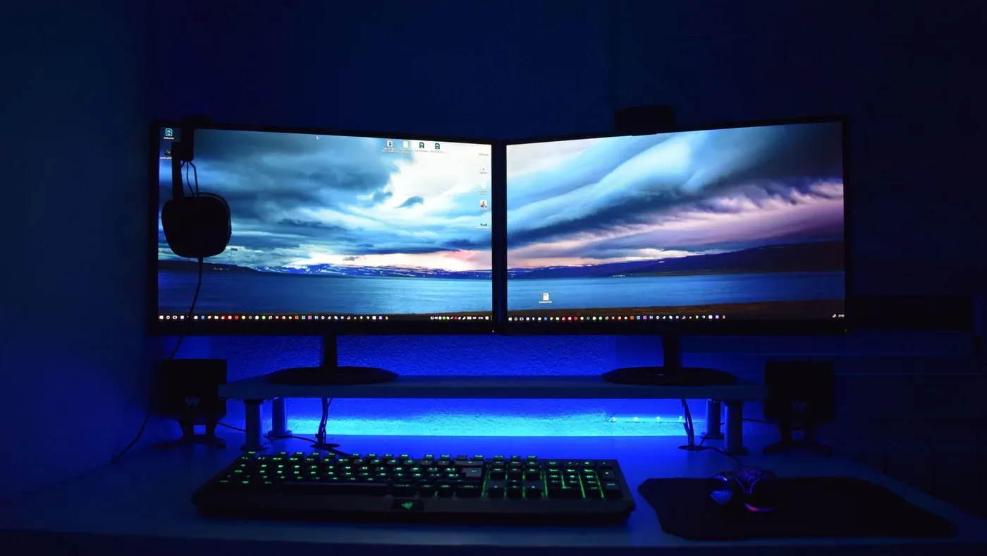Dubbla skärmar med blått ljus på en gamingplats.