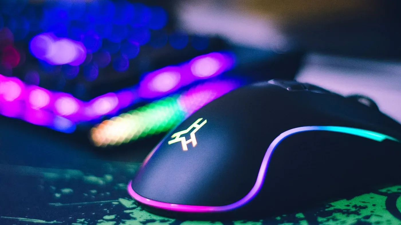 Närbild på en färgglad gamingmus bredvid ett rgb-belyst tangentbord