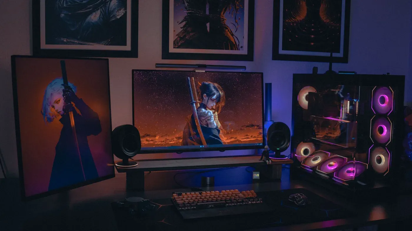 Skrivbord med rgb-belyst dator och skärm som visar färgstark grafik